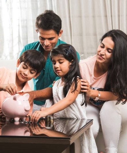 Husband, wife, son and daughter putting money into a piggy bank. 
